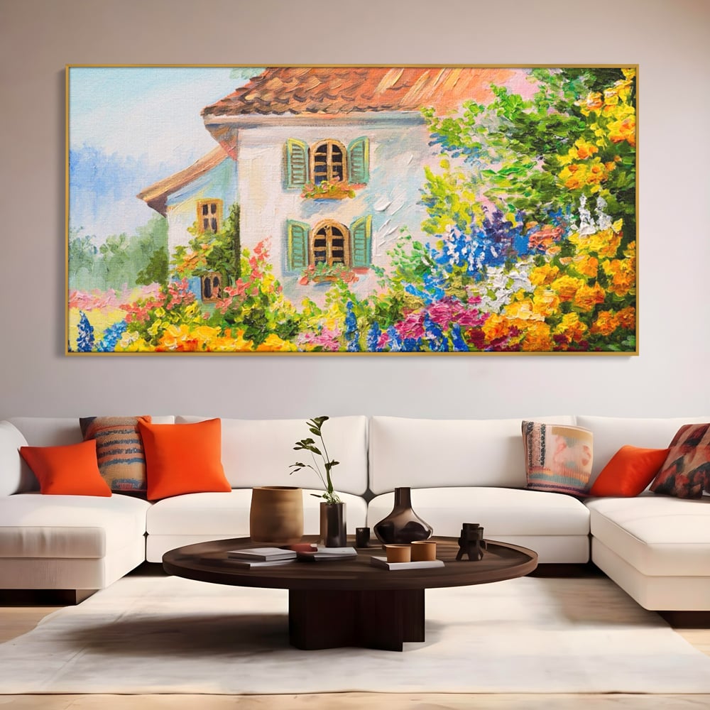 Tablou canvas cu pictura cu casa alba si flori, in rama de aluminiu auriu, pe perete intr-un living